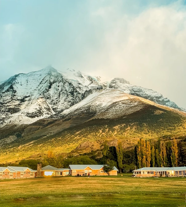 a field with a mountain in the background, shutterstock, light breaks through the roofs, patagonian, military camp in the background, beautiful morning