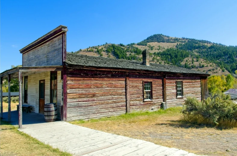 an old wooden building sitting on the side of a road, by Brigette Barrager, shutterstock, in an old west cabin, wide long view, museum photo, boarded up