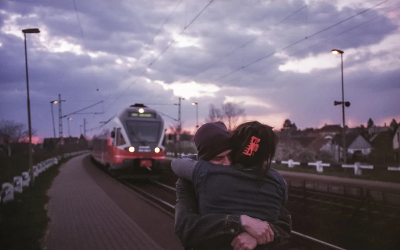 a couple of people that are standing in front of a train, a picture, by Jan Konůpek, unsplash, romanticism, hugs, end of the day, shot on hasselblad, happy friend