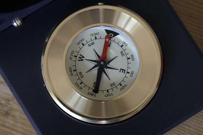 a clock sitting on top of a wooden table, compass, centred position, button potenciometers, top down photo at 45 degrees