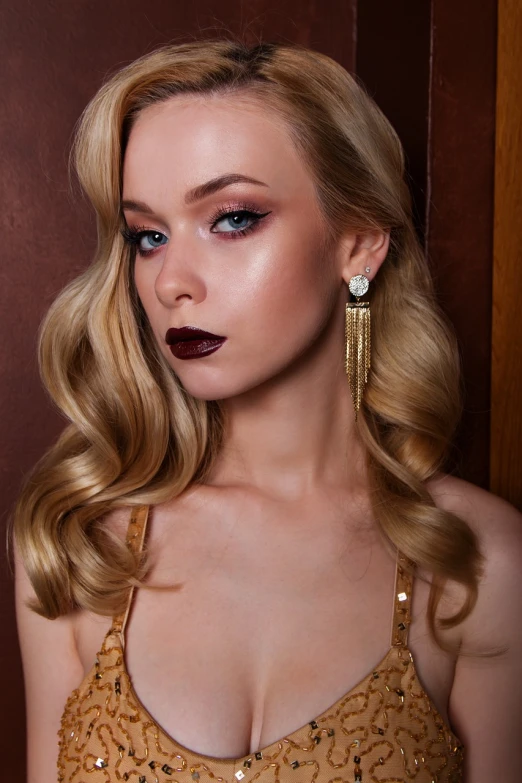 a woman in a gold dress posing for a picture, a portrait, inspired by Emma Andijewska, trending on cg society, long earrings, dark red lips, close up of a blonde woman, full product shot