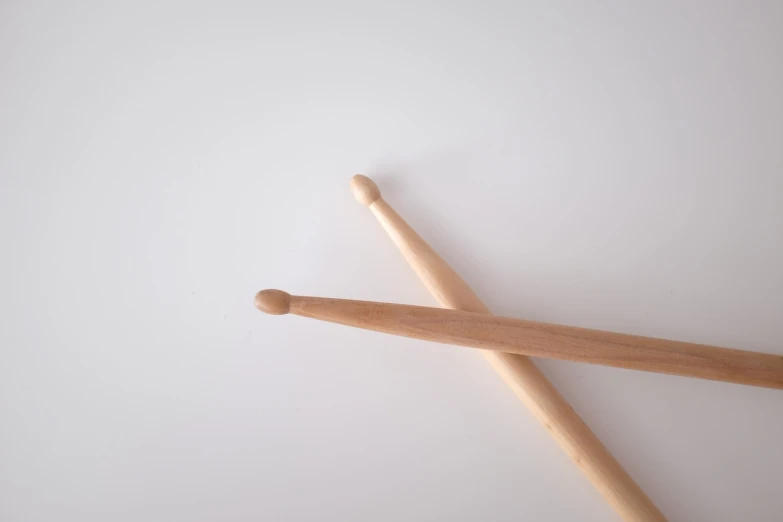 a pair of drumsticks sitting on top of a table, inspired by Peter Maxwell Ewart, set against a white background, view from the ground, tool, easy to understand