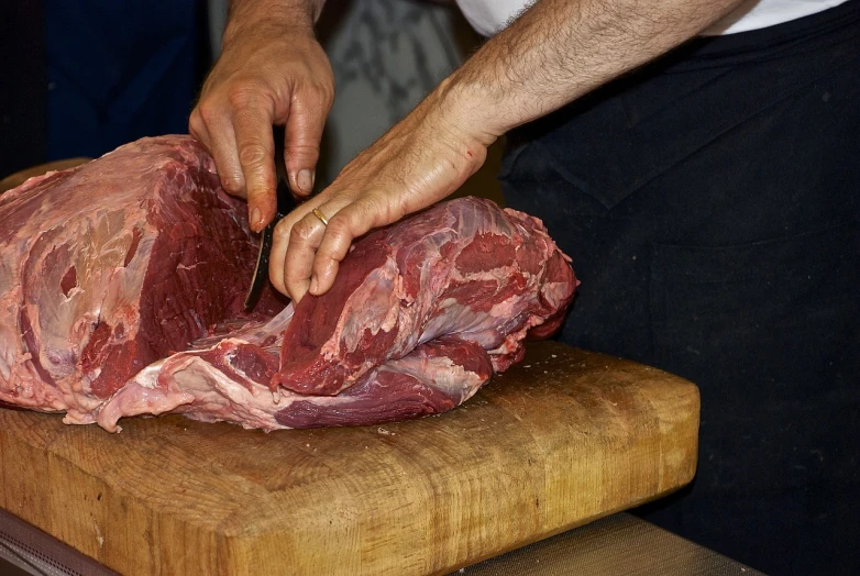a person cutting a piece of meat on a cutting board, a picture, by Jan Rustem, calf, real hands, english, eradication