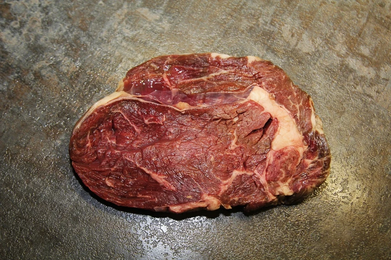 a piece of meat sitting on top of a table, by Robert Zünd, flickr, aerial iridecent veins, back facing, bovine, super realistic food picture