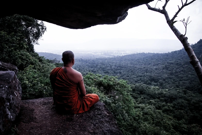 a monk sitting on the edge of a cliff, shutterstock, in jungle forest peak, very known photo, underground temple, stock photo