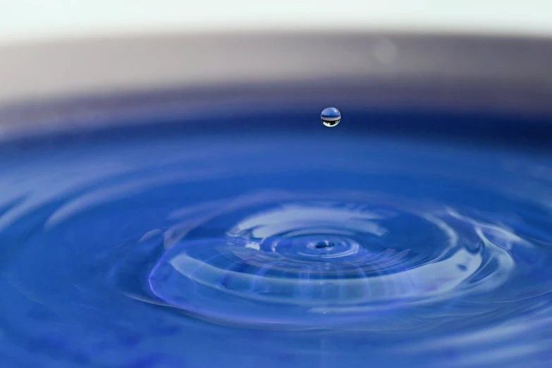 a blue bowl with a drop of water in it, a macro photograph, ripple effect, 4k high res, shallow focus background, highly detailed product photo