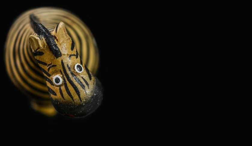 a close up of a zebra figurine on a black background, inspired by Augustin Meinrad Bächtiger, flickr, cobra, steampunk rubber duck, worm's eye view from the floor, shot on sony alpha dslr-a300, glass beads clay amulets