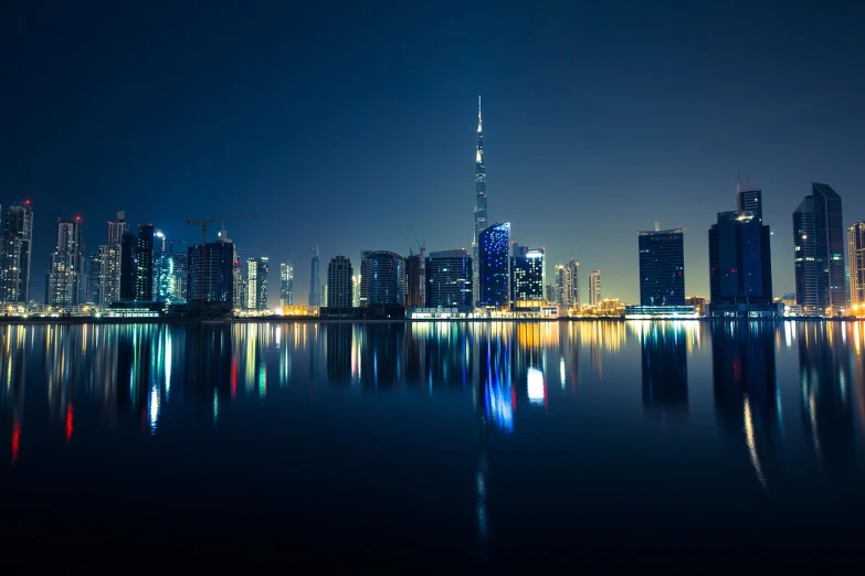 a view of a city at night from across the water, by Bernardino Mei, pexels contest winner, hurufiyya, dubai, view from the lake, true realistic image, shot with a canon 20mm lens