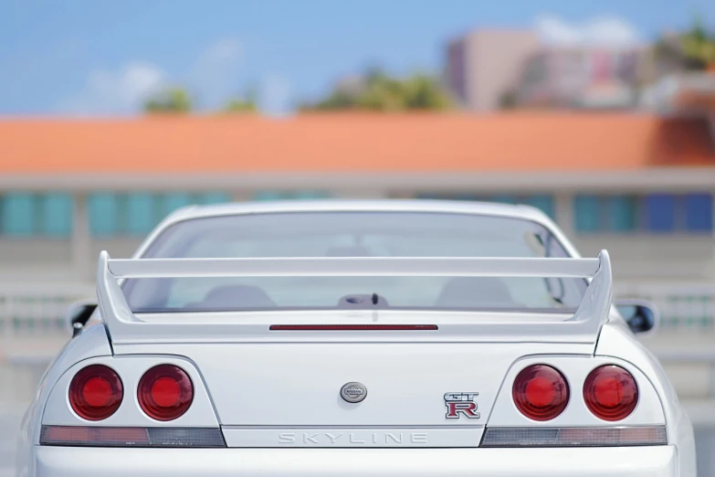 a white car parked in front of a building, by Murakami, unsplash, realism, nissan gtr r 3 4, close-up shot from behind, 4 k vertical wallpaper, on a sunny day