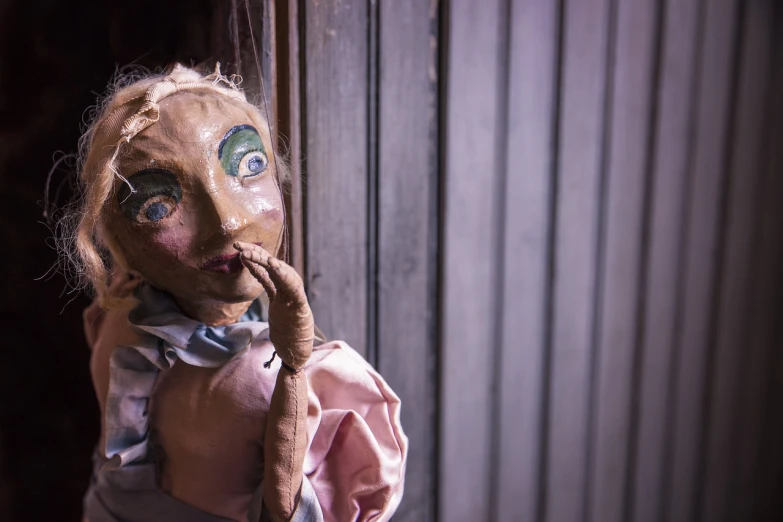 a close up of a doll near a door, a portrait, by Elsa Bleda, shutterstock, folk art, ventriloquist dummy, dilapidated look, hand on her chin, in an attic