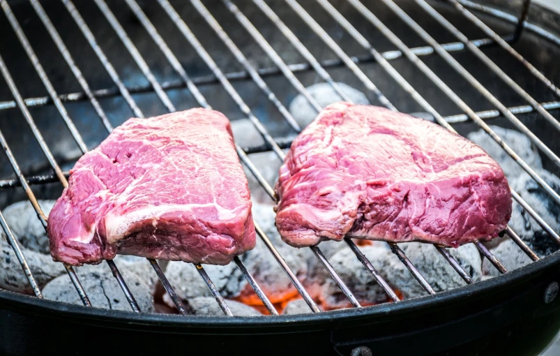 two steaks are cooking on a grill, by Joe Bowler, shutterstock, close up half body shot, usa-sep 20, raku, bottom body close up