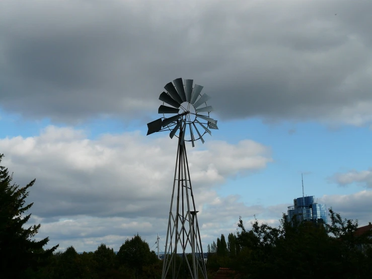 a windmill sitting on top of a lush green field, flickr, hurufiyya, city park, caulfield, against a stormy sky, cowboy