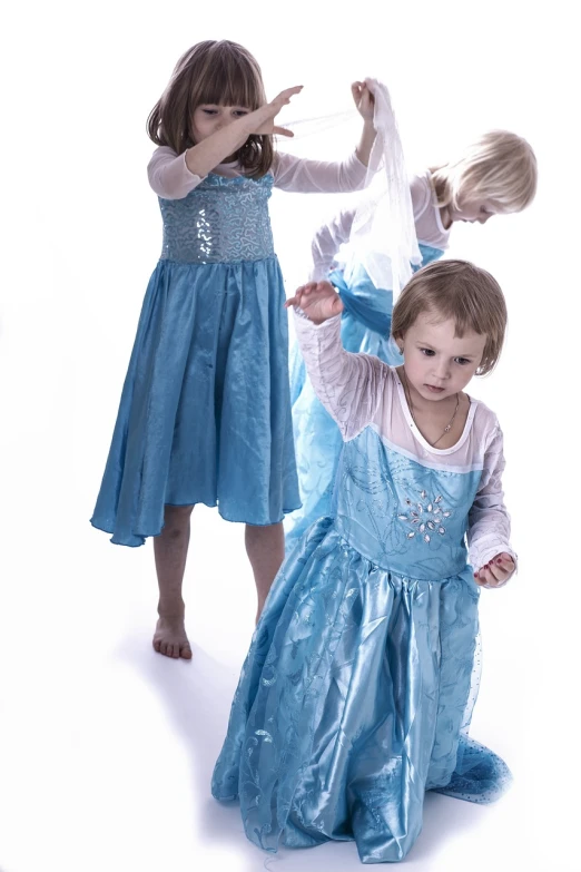 a couple of little girls standing next to each other, inspired by Elsa Beskow, shutterstock, process art, icey blue dress, three futuristic princes, professional studio photograph, captures emotion and movement