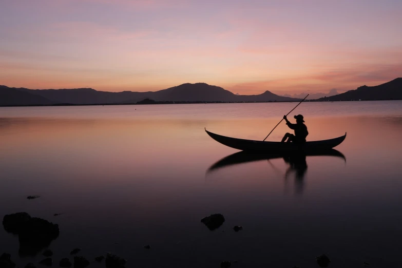 a man in a boat on a lake at sunset, pexels contest winner, hoang lap, slice of life”, at gentle dawn pink light, stick