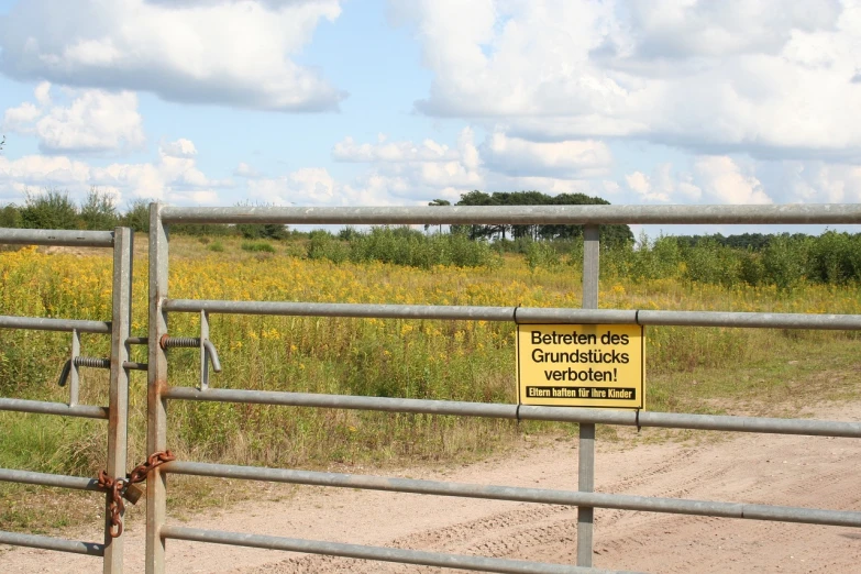 a gate that has a sign attached to it, a photo, by Dietmar Damerau, prairie, bioremediation, flowerfield, file photo