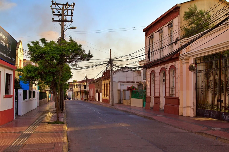 a street lined with buildings and a telephone pole, by Juan Carlos Stekelman, flickr, morning glow, colonial style, small town surrounding, gunfire