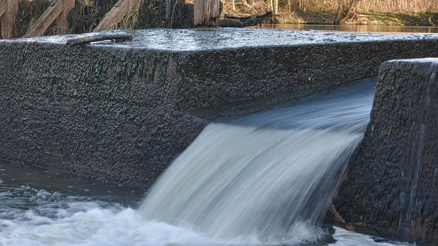 a small waterfall in the middle of a river, by Jan Rustem, pixabay, hurufiyya, sewage, half image, mill, february)