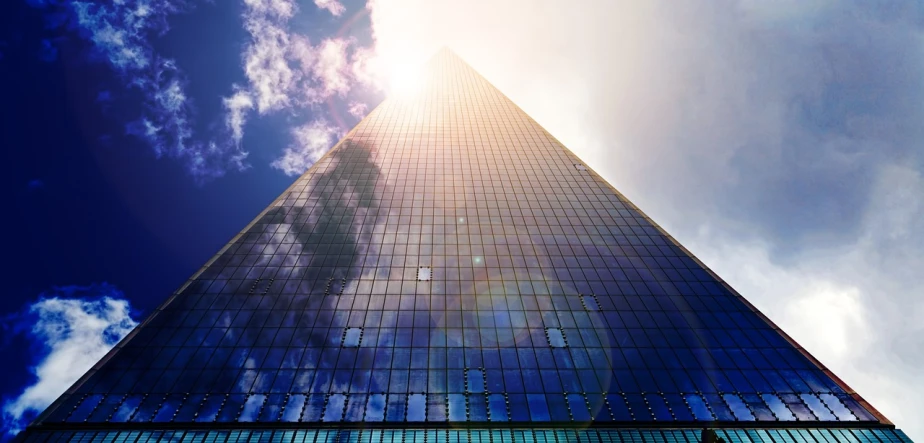 a very tall building with a lot of windows, by Jan Rustem, unsplash, triangle, the sun shines in, under blue clouds, render to resolute perfection