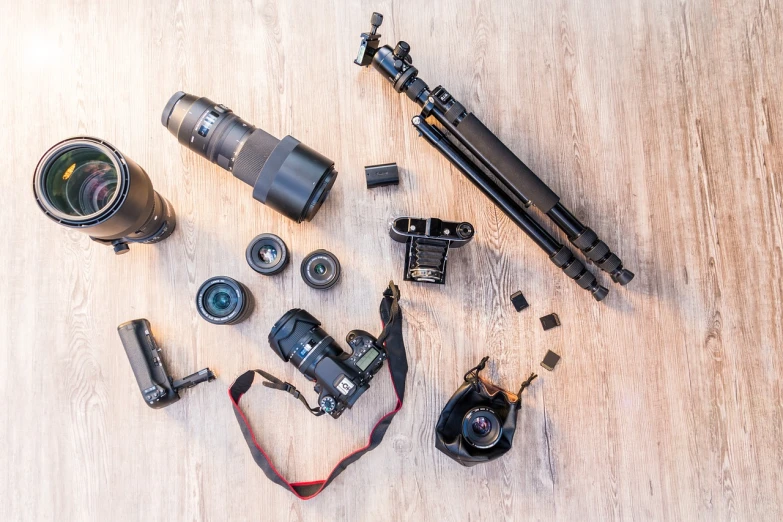 a camera sitting on top of a wooden floor next to a tripod, a picture, shutterstock, cameras lenses, knolling, covered with tar. dslr, lot of details