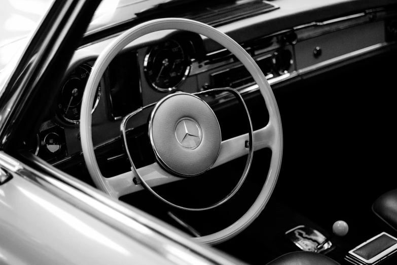 a close up of a steering wheel in a car, a black and white photo, by Matthias Weischer, classic beauty, mercedez benz, soft colors mono chromatic, 60s style