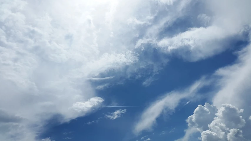 a plane flying through a cloudy blue sky, a picture, 5 feet away, ceremonial clouds, background image, looking up onto the sky