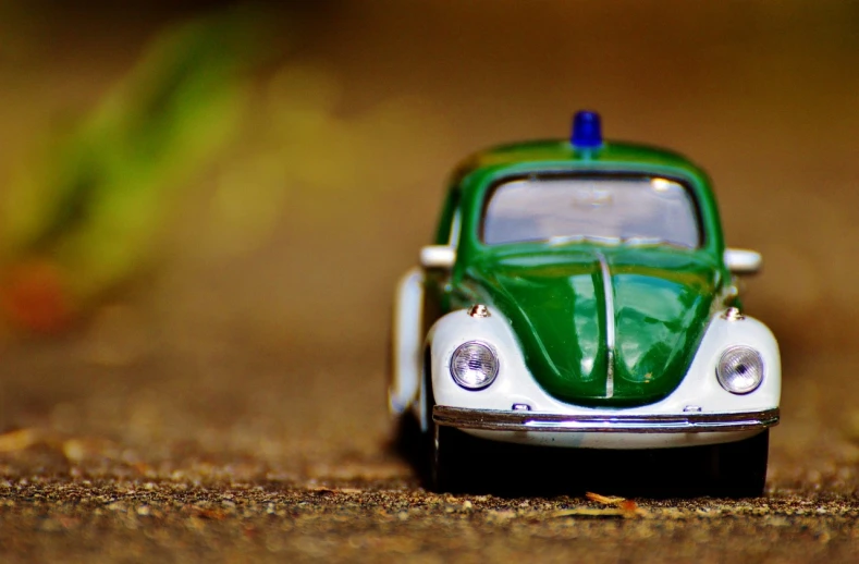 a toy car that is sitting on the ground, unsplash, photorealism, green light, beetle-inspired, police car lights, road trip