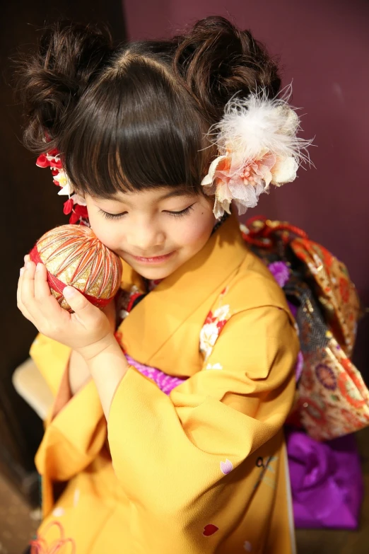 a little girl holding a ball of yarn, a picture, inspired by Otake Chikuha, shutterstock, beautiful costume, material is!!! plum!!!, traditional beauty, celebration