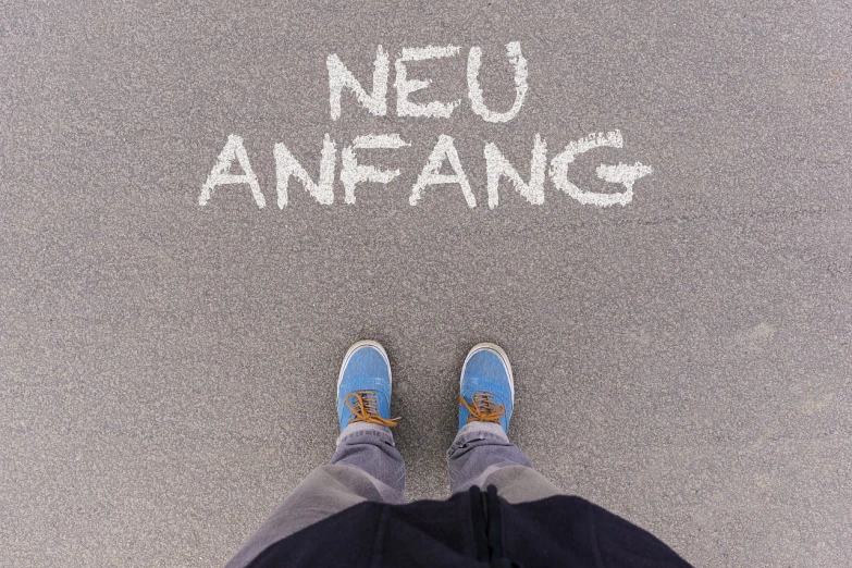a person standing in front of the words neu anfang, foot path, far!!!!!!! away, german, a new