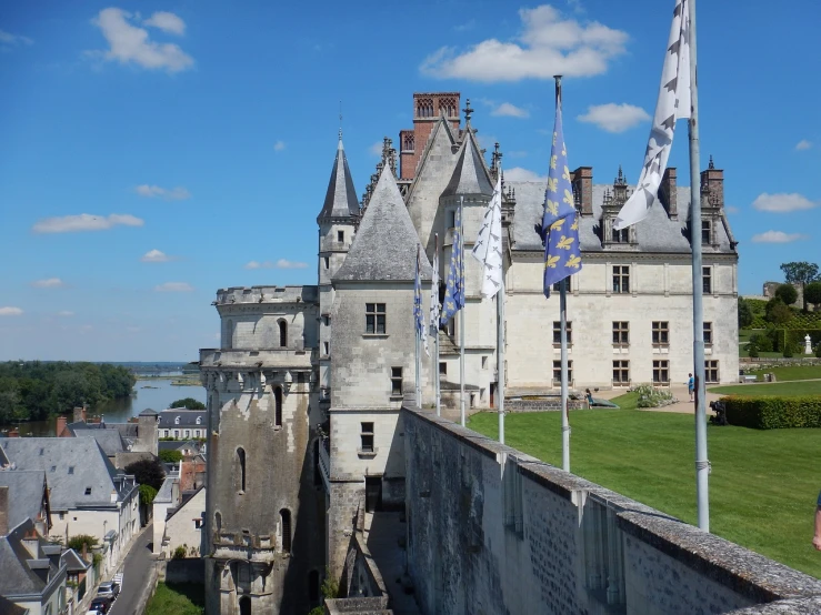 a man standing on top of a wall next to a building, art nouveau, medieval castle, flags, wide shot photo, traveling in france