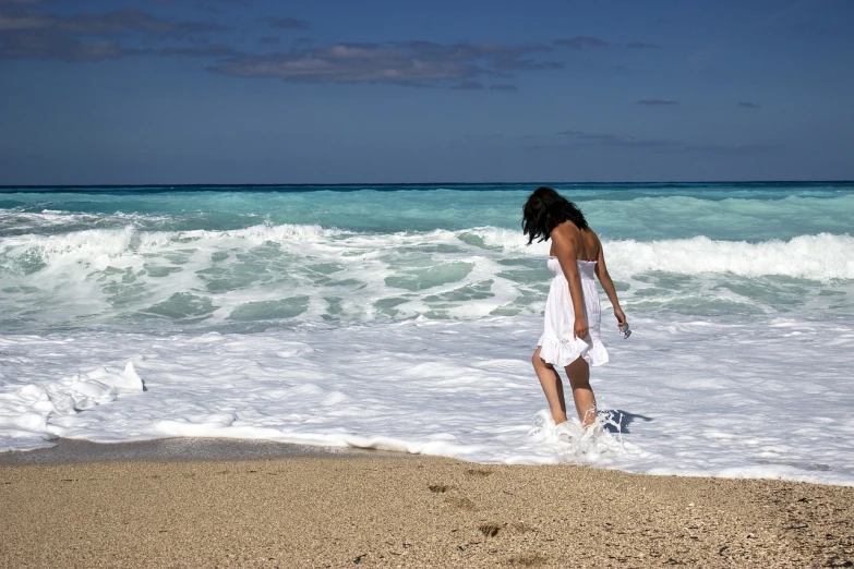 a woman in a white dress walking into the ocean, by Niko Henrichon, pixabay contest winner, happening, wikimedia, sea foam, mischievous!!, happy italian beach scene