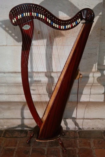 a large wooden harp sitting on top of a brick floor, inspired by Balázs Diószegi, flickr, hanging in the louvre, cable plugged into cyberdeck, archs, stems