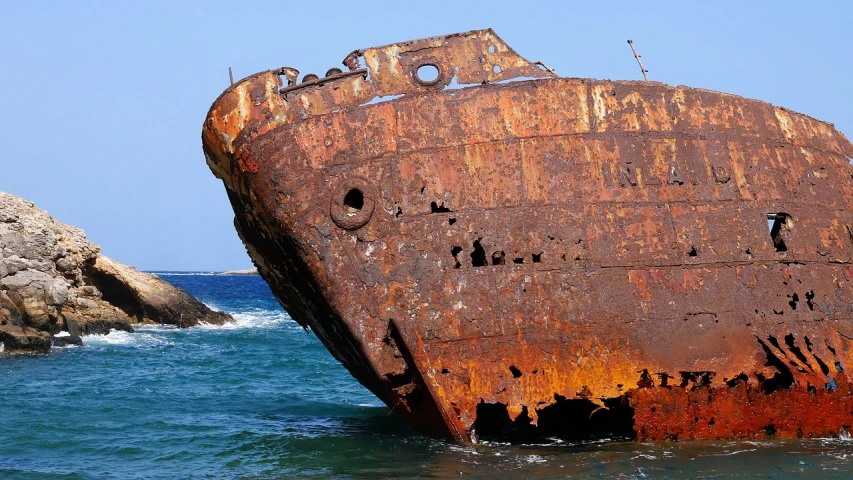 a rusted ship sitting in the middle of the ocean, close - up profile, shoreline, stern like athena, striking pose