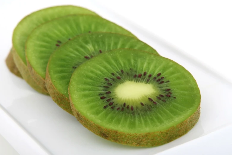 three slices of kiwi on a white plate, by Ikuo Hirayama, hurufiyya, high res photo, istockphoto, emerald, hybrid