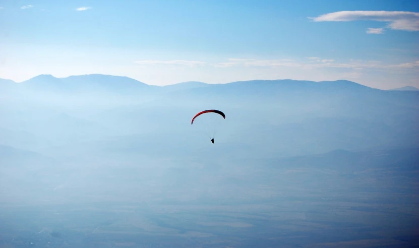 a paraglider in the sky with mountains in the background, pexels, figuration libre, faint dust in the air, azamat khairov, floating in empty space, benjamin vnuk