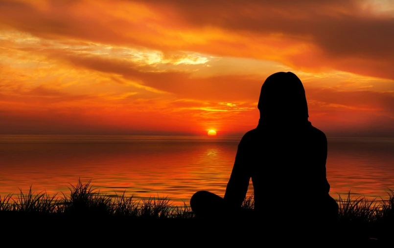 a silhouette of a person sitting in front of a sunset, shutterstock, beautiful girl on the horizon, meditation, stock photo