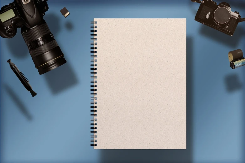 a notebook sitting on top of a table next to a camera, by Andrei Kolkoutine, pixabay, conceptual art, wrapped blue background, realistic detailed background, stock photo, flat lay