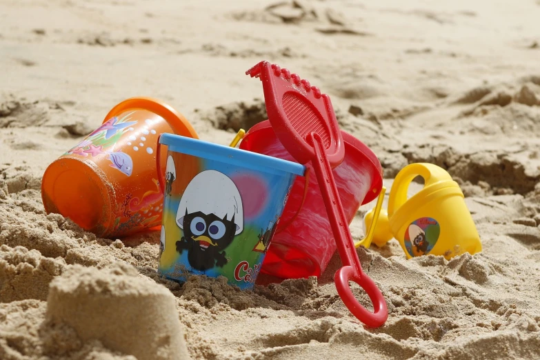 a couple of buckets sitting on top of a sandy beach, a picture, pixabay, plasticien, minions, happy meal toy, they might be crawling, multicoloured