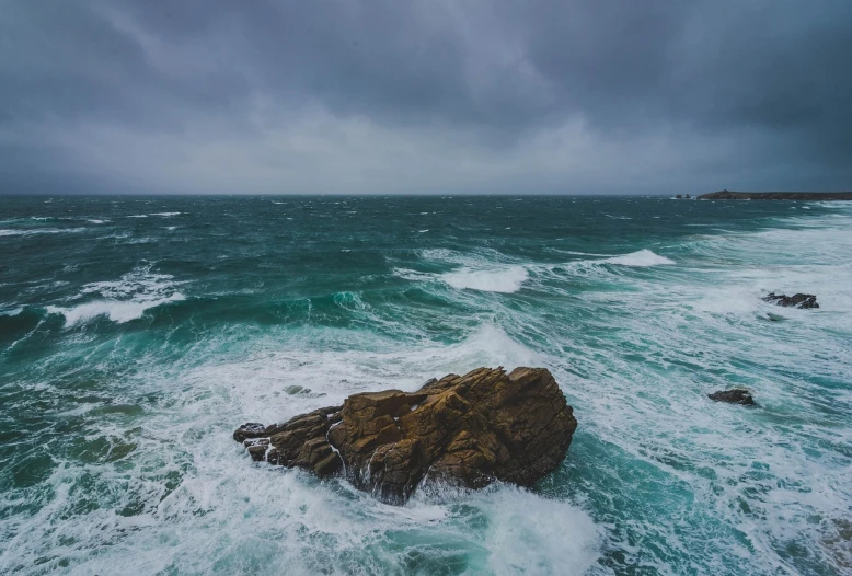 a large rock in the middle of a body of water, a picture, by Matthias Weischer, pexels, romanticism, stormy ocean, cornwall, stock photo, stormy wheater