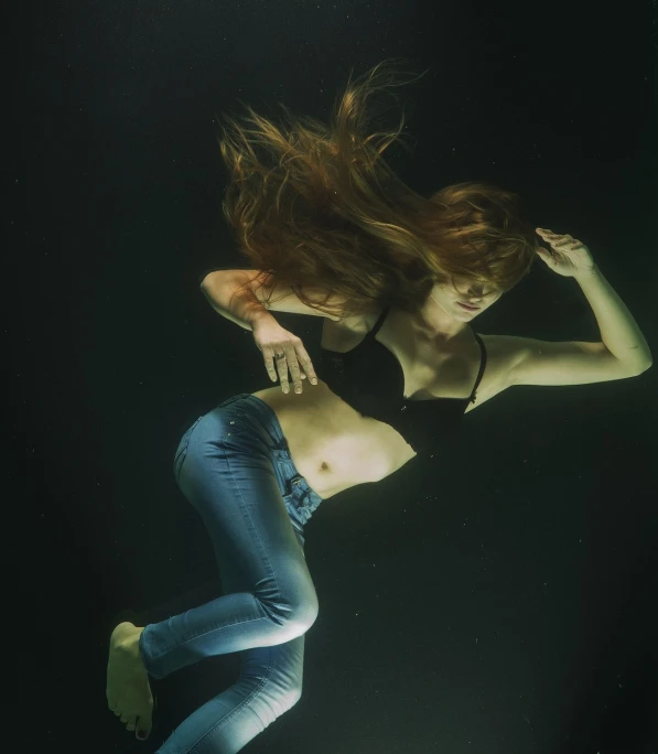 a woman in a bikini swims under water, a portrait, figuration libre, shot at dark with studio lights, hair is floating, floating in space, young redhead girl in motion