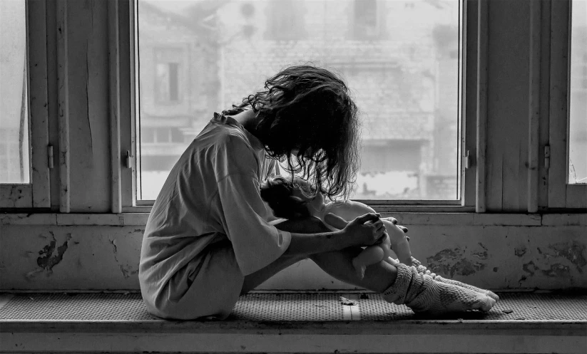 a black and white photo of a person sitting on a window sill, feeling of dread, hugging her knees, iralki nadar, disheveled