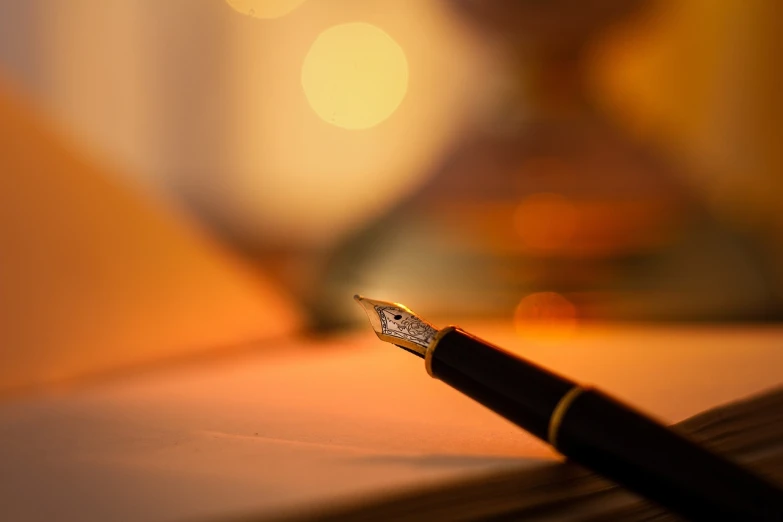 a pen sitting on top of a piece of paper, by Thomas Häfner, shutterstock, romanticism, warm glow from the lights, bokeh photo