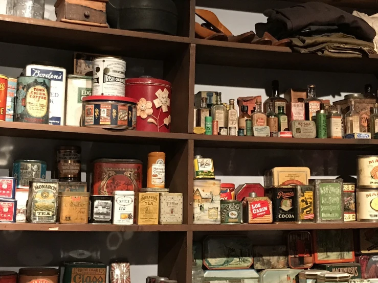 a shelf filled with lots of different types of tins, folk art, smokey room, moma, old shops, photo taken in 2018