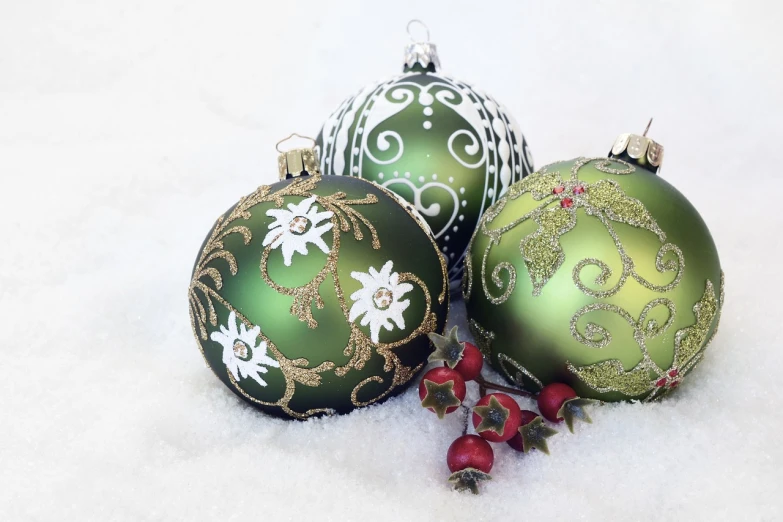 a close up of three christmas ornaments in the snow, inspired by Ernest William Christmas, baroque, an elegant green, decorated with flowers, hand painted style, colour photo