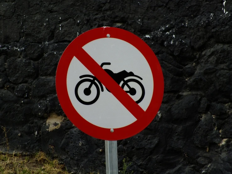 a red and white sign sitting on the side of a road, a poster, pixabay, graffiti, sitting on a motorcycle, azores, no - text no - logo, forbidden