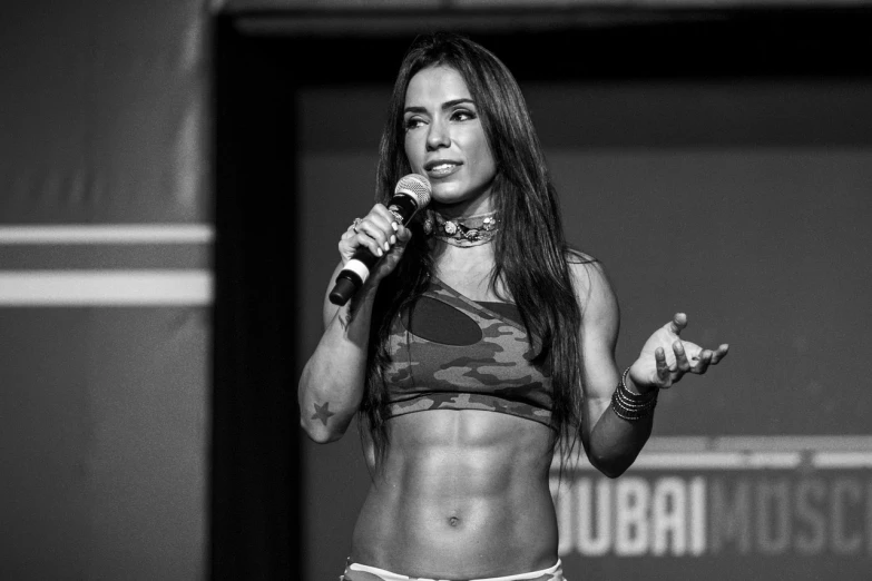 a black and white photo of a woman holding a microphone, by Giorgio Cavallon, reddit, arabesque, ifbb fitness body, dubai, dua lipa, presentation