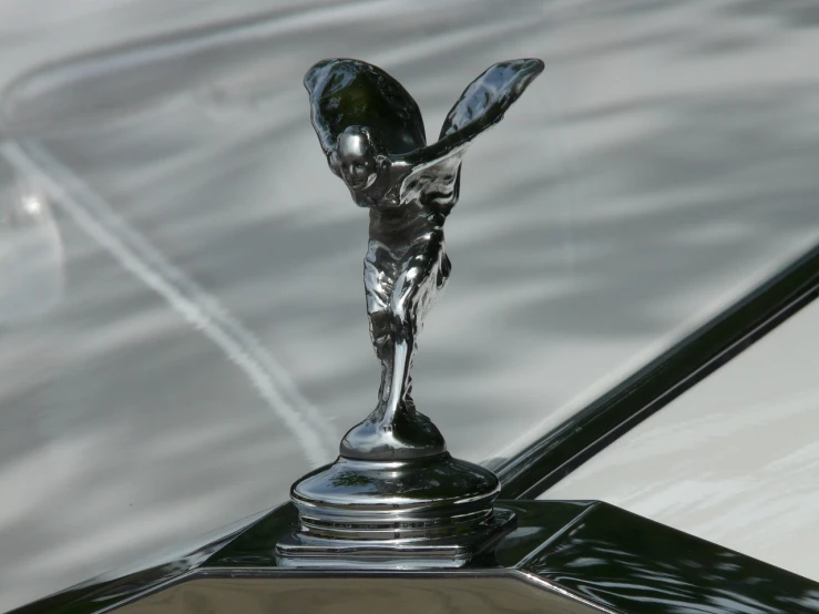 a close up of a hood ornament on a car, an art deco sculpture, by Roger Cecil, flickr, arabesque, mechanical angel, platinum, wraith, ultrafine detail ”