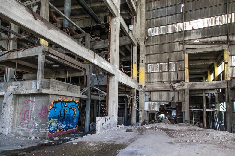 a building that has a bunch of graffiti on it, by Arnie Swekel, flickr, dark abandoned cyberpunk factory, concrete pillars, tourist photo, inside the building