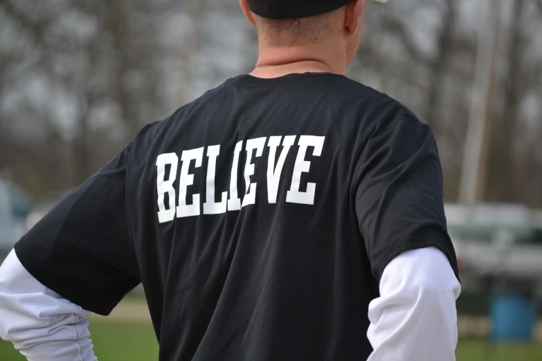 the back of a baseball player wearing a believe shirt, a picture, by Neil Blevins, pixabay, acronym, reflective, college, photograph credit: ap