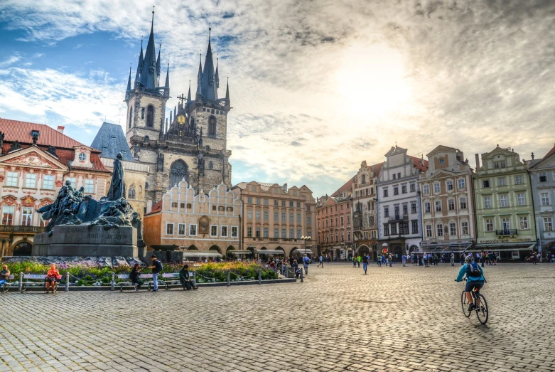 a man riding a bike down a cobblestone street, a photo, by karolis strautniekas, shutterstock, baroque, majestic spires, a wide open courtyard in an epic, city square, straw