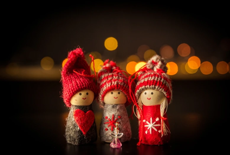 a couple of dolls sitting next to each other on a table, a picture, by Etienne Delessert, pexels, christmas lights, against dark background, trio, miniature product photo